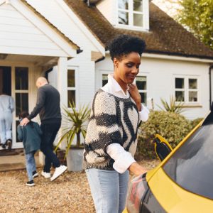 woman-charging-electric-car-ev-on-driveway-outside-2023-03-24-21-16-25-utc compressed